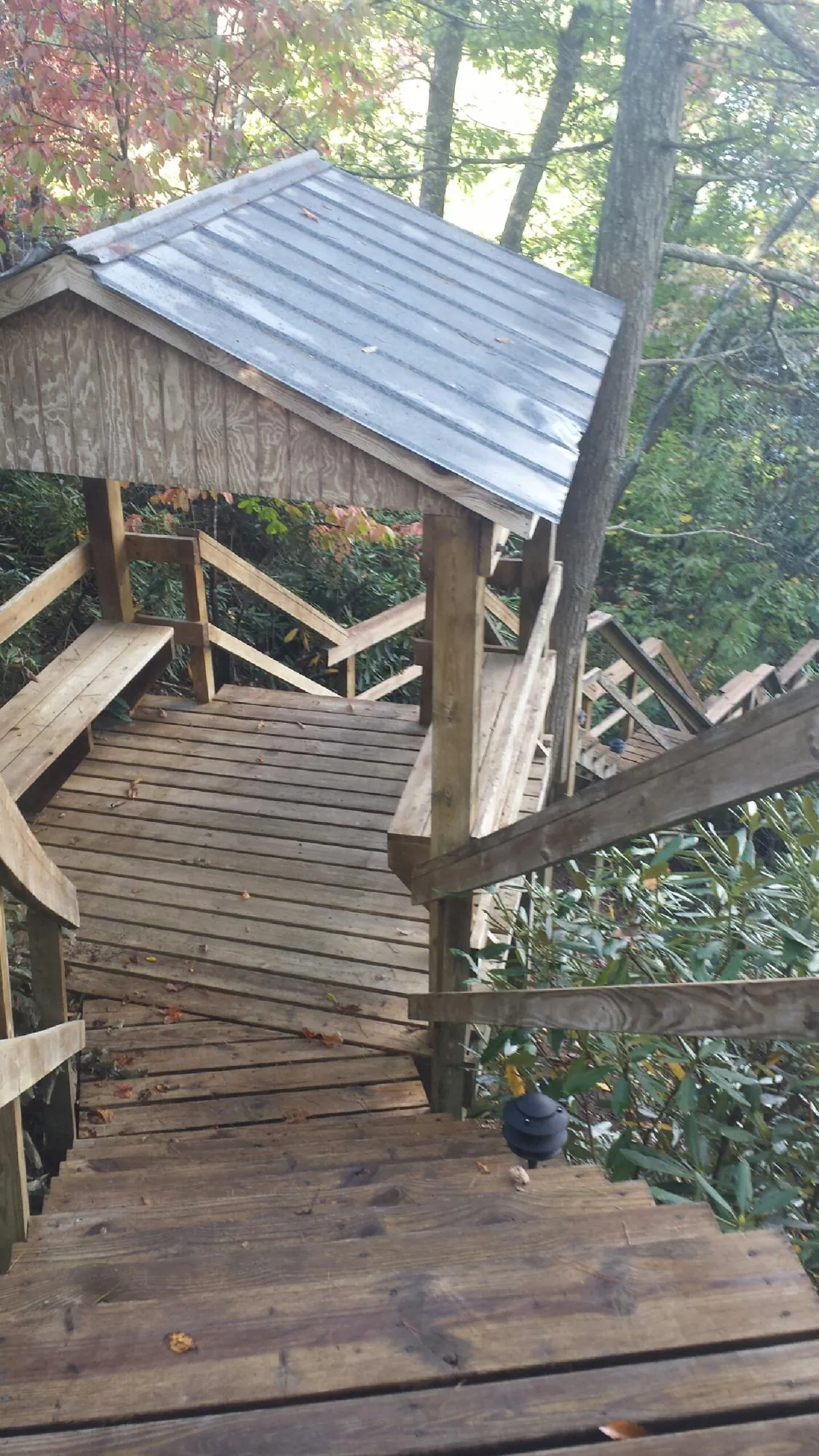 Metal roofed shelter over wooden steps on a wooded walkway — Skylight Repair & Installation work by our crew in Seaside